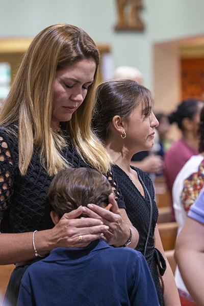 Tatiana Amara comforts her children, Isabella Cisternino, 11, and Luca Cisternino, 9, during the Mass. Isabella's best friend, Lucia Guara, perished along with her brother and parents in the Champlain Towers South collapse. Isabella and Lucia had made their first Communion together at St. Joseph, which hosted the memorial Mass on the anniversary of the tragedy, June 24, 2022.