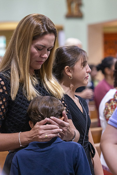 Tatiana Amara consuela a sus hijos, Isabella Cisternino, de 11 años, y Luca Cisternino, de 9, durante la Misa. La mejor amiga de Isabella, Lucía Guara, pereció junto con su hermano y sus padres en el derrumbe de las Torres Champlain South. Isabella y Lucía habían hecho juntas su primera comunión en St. Joseph que celebró la Misa conmemorativa en el aniversario de la tragedia, el 24 de junio de 2022.