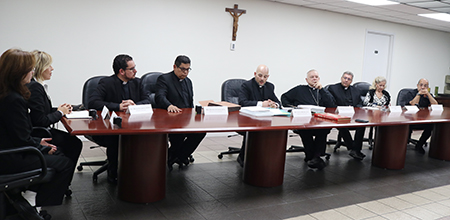 Members of the ecclesiastical court formed in Miami to investigate an alleged miracle attributed to Blessed José Gregorio Hernández and Archbishop Thomas Wenski, center, listen to Father Luis Rivero, the episcopal delegate, during the ceremony where the results of the investigation were sealed and sent to Rome. The ceremony took place, June 17, 2022, at the archdiocesan Pastoral Center.