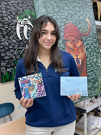 Senior Christina Carvajal holds the canvases she created for the St. Brendan High School art program's service project "I Care Canvas."