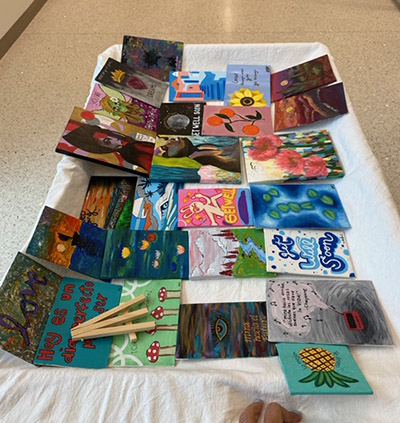 A Christine E. Lynn Rehabilitation Center therapist spreads canvases created by St. Brendan High art students on a cart and delivers them to the patients for selection.