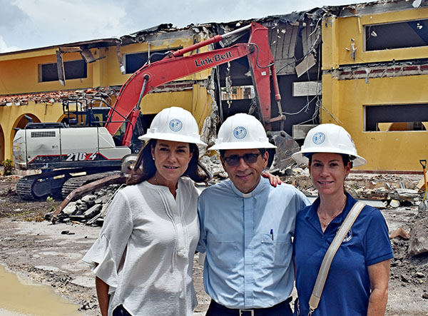 Los l&iacute;deres de la campa&ntilde;a de construcci&oacute;n de la iglesia St. Agnes hacen una pausa mientras la maquinaria derriba el antiguo edificio, el 26 de julio de 2022. Desde la izquierda, Anabel Stevens, administradora de negocios; P. Juan Carlos Paguaga, p&aacute;rroco; y Marcela Zamora Erana, encargada del fondo de construcci&oacute;n.