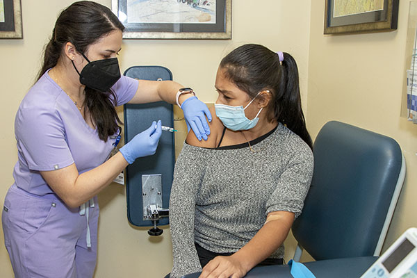 Nesli Akinci, estudiante de tercer año de Medicina Osteopática en la universidad Nova Southeastern, vacuna a una niña de 11 años que llegó hace un mes de Honduras, el 29 de julio de 2022, en Camillus Health Concern de Miami. El personal médico de la clínica proporciona vacunas, exámenes visuales y servicios dentales a niños inmigrantes recién llegados, independientemente de su estatus legal o capacidad económica.