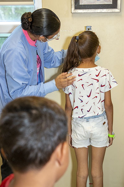 Una asistente médica mide la altura y el peso de una niña, el 29 de julio de 2022 en el Camillus Health Concern de Miami. El personal médico ofrece vacunas, exámenes visuales y servicios dentales a niños inmigrantes recién llegados, independientemente de su situación legal o de su capacidad económica.