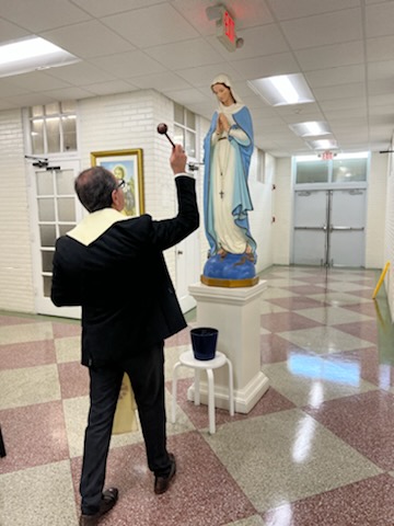Newly appointed parish adminstrator Father Luis Flores blesses an image of Mary in an interior hallway at Sts. Peter and Paul School in Miami in preparation for the start of the 2022-23 school year.