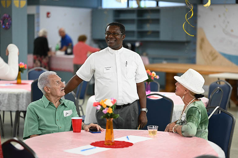Father Jean Jadotte, newly installed pastor of St. Pius X Parish in Fort Lauderdale, greets parishioners Aug. 16, 2022, during a social event, "Getting to know St. Pius X: The Pope of the Eucharist," which was designed to illuminate his life during the Eucharistic Revival that began on Corpus Christi Sunday. The revival invites Catholics throughout the Miami Archdiocese and throughout the country to deepen their faith in the real presence of Jesus in the Blessed Sacrament. It will culminate in a national Eucharistic Congress in July 2024 in Indianapolis, Indiana.