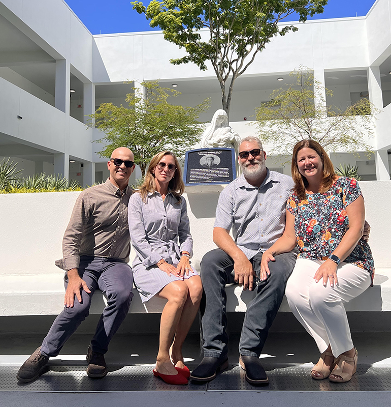 Mike and Mari Quesada, right, pose with Orlando and Monique Garcia, Danny's godparents, in front of the image of Mary that adorns "Coach DQ Courtyard," dedicated to the memory of their son, Danny Quesada. He passed away of cystic fibrosis during his senior year in 2019. The dedication and blessing took place Sept. 8, 2022.