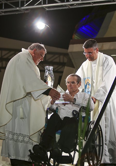 El P. José Espino, rector de la Ermita, a nombre de la Archicofradía de la Ermita de la Caridad le entregó a Rogelio Zelada una placa de reconocimiento por su esmerado cuidado y amor incondicional a la bendita imagen de la Virgen de la Caridad, el 8 de septiembre, durante la celebración anual de la Virgen en Miami. Los acompaña el P. Manny Álvarez, párroco de Little Flower en Coral Gables.