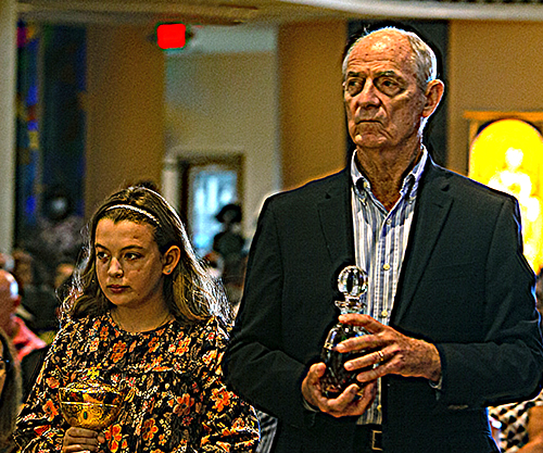 Lucy Gonzalez, 10, and her great uncle, Marty Mennes, bring the offertory gifts to Archbishop Thomas Wenski during the Mass kicking off the 75th anniversary of St. Rose of Lima Parish in Miami Shores, Oct. 9, 2022.