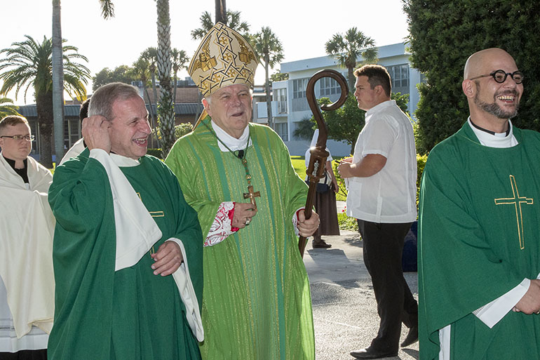 Archbishop Thomas Wenski shares a joke with Msgr. Pablo Navarro, left, rector of St. John Vianney College Seminary, and Father Luis Rivero, assistant administrator and pre-theology program coordinator, as he prepared to celebrate the opening Mass of the annual Catechetical Conference, which brought around 600 religious education and Catholic school teachers to St. Brendan High School, Oct. 29, 2022.