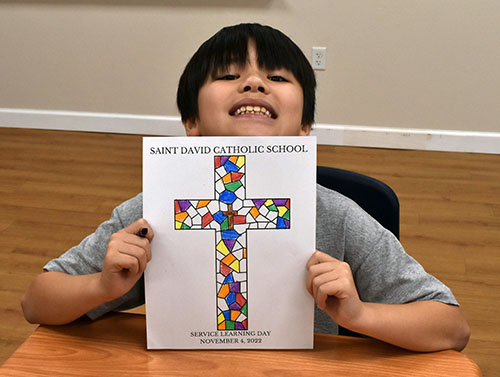 Third-grader Preston Deve shows a stained-glass picture of a cross he made as a keepsake for the Service Learning Day.