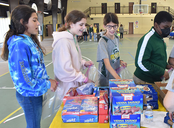 Students at St. David School form an assembly line to assemble food bags for the homeless.