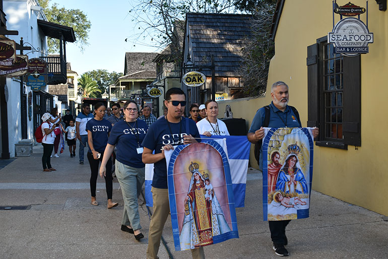 Participantes en el XVIII Encuentro Regional de la pastoral hispana en el sureste de los EE.UU. atraviesan la hist&oacute;rica St. George Street en San Agust&iacute;n portando banderas y banderines con las advocaciones marianas El Encuentro tuvo lugar del 12 al 15 de octubre de 2022.