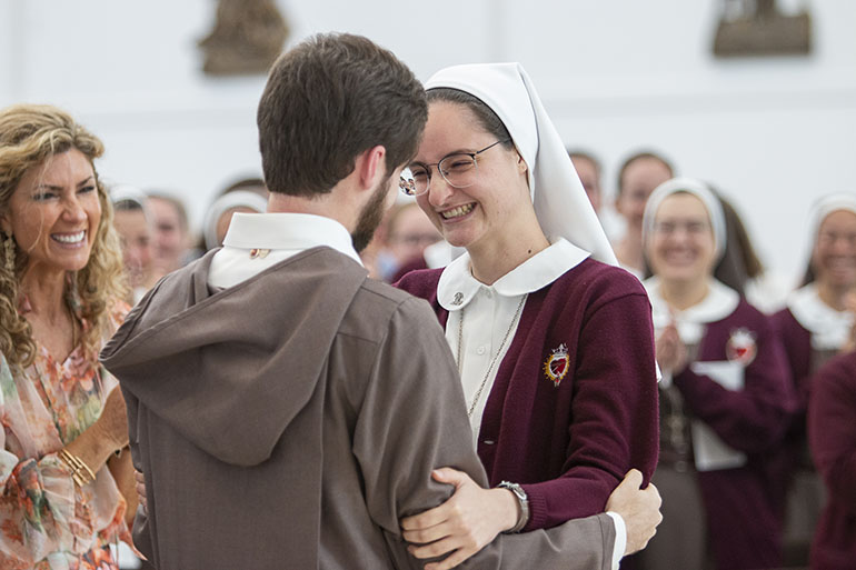 Brother Iñigo Johnpaul is congratulated by his sister, novice Andrea Isla, after professing first vows as a Servant of the Pierced Hearts of Jesus and Mary, Oct. 22, 2022. He is the first religious brother of the community. At left is their mother, Andrea Isla.