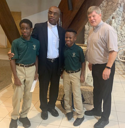 Bishop Charles Peters Barthélus of Port-de-Paix, Haiti, poses with Father Steven O'Hala, St. David's pastor, and fifth graders Caiden Francois and Darren Clermont during his October 2022 visit to St. David School in Davie.