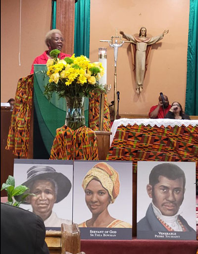 Katrenia Reeves-Jackman, director of the Office of Black Catholic Ministry, speaks during the Mass marking Black Catholic History Month, which Archbishop Thomas Wenski celebrated at St. Stephen Church in Miramar, Nov. 5, 2022. In front are some images of Black Catholics from the U.S. currently being proposed for sainthood.