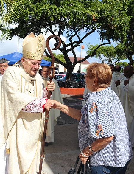 Momentos antes de iniciar la Misa de 75 aniversario de la parroquia St. Michael the Archangel, el Arzobispo Thomas Wenski saluda a una feligresa en la puerta de la iglesia, el 6 de noviembre de 2022.
