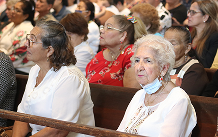 Inailbis de la Torre, right, a parishioner of St. Michael's for more than 40 years, listens to Archbishop Thomas Wenski's homily during the parish's 75th anniversary Mass, Nov. 6, 2022.