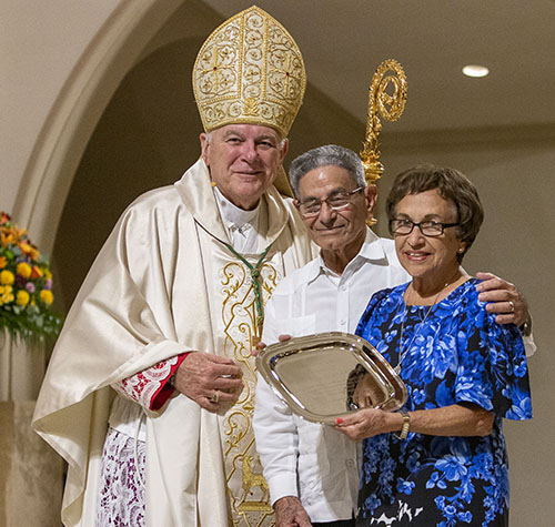Archbishop Thomas Wenski presents Roberto and Clara Gesni, of St. Michael the Archangel Parish in Miami, with the 2022 One in Faith award during the annual Thanks-for-Giving Mass hosted by the archdiocesan Office of Development to honor those who contribute faithfully to the ABCD. The Mass was celebrated Nov. 19, 2022 at St. Mary Cathedral in Miami.