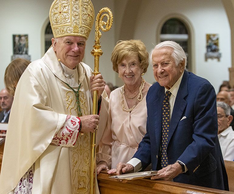 Archbishop Thomas Wenski presents Winifred and Joseph Amaturo, of St. John the Baptist Parish in Fort Lauderdale, with the 2022 One in Charity award during the annual Thanks-for-Giving Mass hosted by the archdiocesan Office of Development to honor those who contribute faithfully to the ABCD. The Mass was celebrated Nov. 19, 2022 at St. Mary Cathedral in Miami.