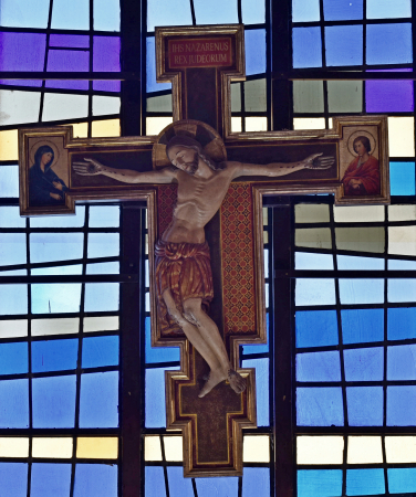 Stylized crucifix dominates the chancel window at St. Hugh Church.