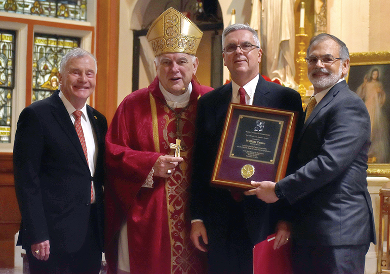 William Castro, second from right, is congratulated after receiving the 2022 Lex Christi, Lex Amoris Award from the Miami Catholic Lawyers Guild during the annual Red Mass, Dec. 1, 2022  at Gesu Church, Miami. From left are Francis X. Sexton, president of the guild; Archbishop Thomas Wenski, main celebrant at the Mass; Castro, and former Florida Supreme Court Justice Raoul Cantero.