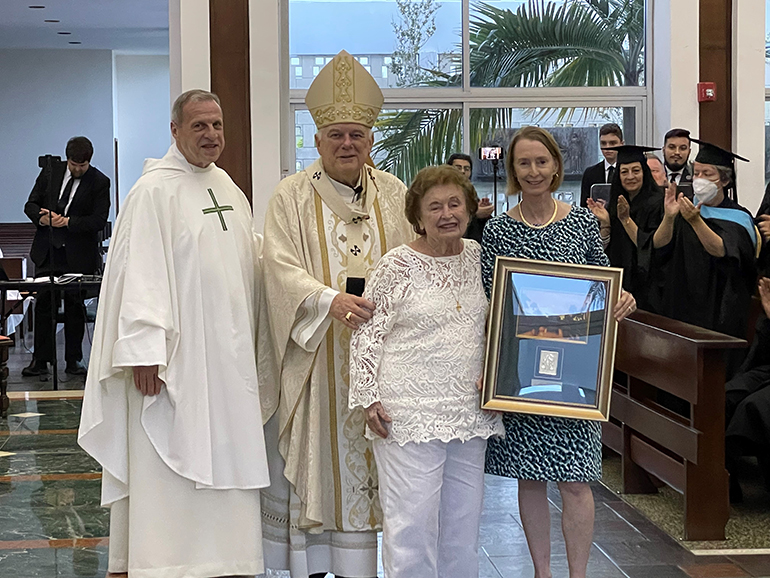 Archbishop Thomas Wenski presents the Curé of Ars award to Sallye Jude, seen here with her daughter, Cecilia Prahl, as Msgr. Pablo Navarro, seminary rector/president, looks on. The presentation took place at the Mass and graduation ceremony for students at St. John Vianney College Seminary in Miami, May 4, 2022.