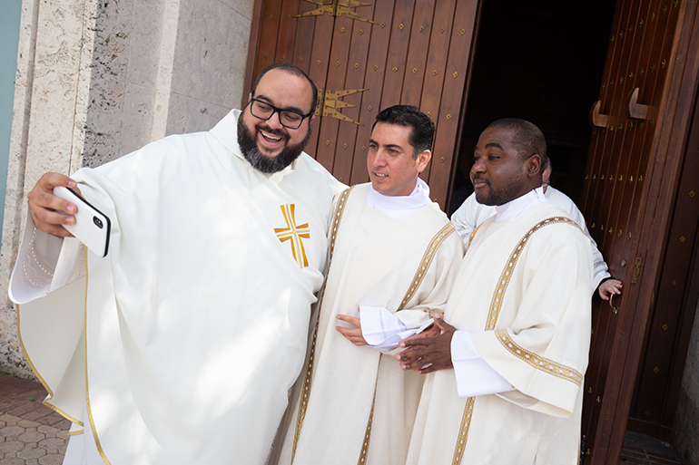 Los diáconos Julio César Vázquez (centro) y Rikinson Bantou (derecha) se toman un selfie con el P. Matthew Gómez, director arquidiocesano de Vocaciones, después de su ordenación al diaconado el 3 de diciembre de 2022, en la Catedral St. Mary en Miami. El diaconado es el último paso antes de su ordenación sacerdotal.