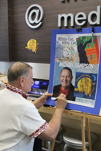 Children's author Michael Sampson signs a promotional poster of his visit to St. Louis Covenant School in Pinecrest on April 29, 2022, after presenting his book "Armadillo Antics." Sampson also visited middle school students at the school and discussed his work as a Fulbright Scholar in Ukraine, which turned into humanitarian work with refugees fleeing the country.