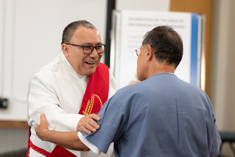 El diácono Edgardo Farias, director del Ministerio de Detención en la Arquidiócesis de Miami, habla con un recluso durante la visita pastoral del arzobispo Thomas Wenski el 8 de junio de 2022 a la Institución Correccional Everglades en el borde occidental del condado de Miami-Dade. La instalación ejecuta un programa piloto incentivado para cultivar un ambiente de aprendizaje y rehabilitación para reducir el comportamiento violento entre los reclusos. La prisión también es única porque tiene un capellán católico de tiempo completo.