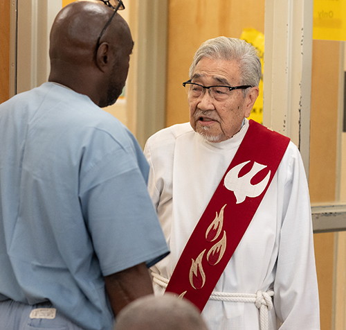 Deacon Alex Lam, fulltime chaplain at Everglades Correctional Institution, speaks with an inmate June 8, 2022, the day Archbishop Thomas Wenski made a pastoral visit to the facility in the western edge of Miami-Dade County.