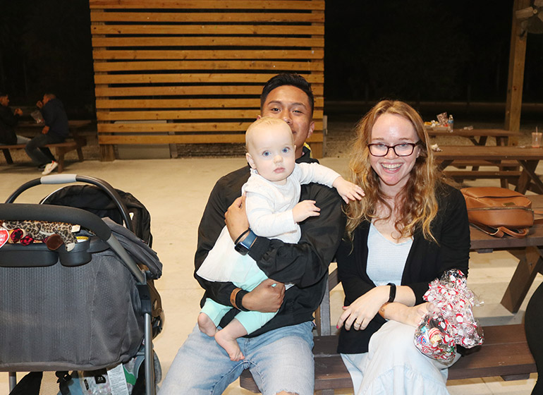 Caroline Hazelton, a foster mother, poses for a photo with 19-year-old Brandon Garcia, who is holding his foster baby sister. The Hazeltons took Brandon into their home for a few months as part of Catholic Charities of Miami's Unaccompanied Refugee Minors Program.