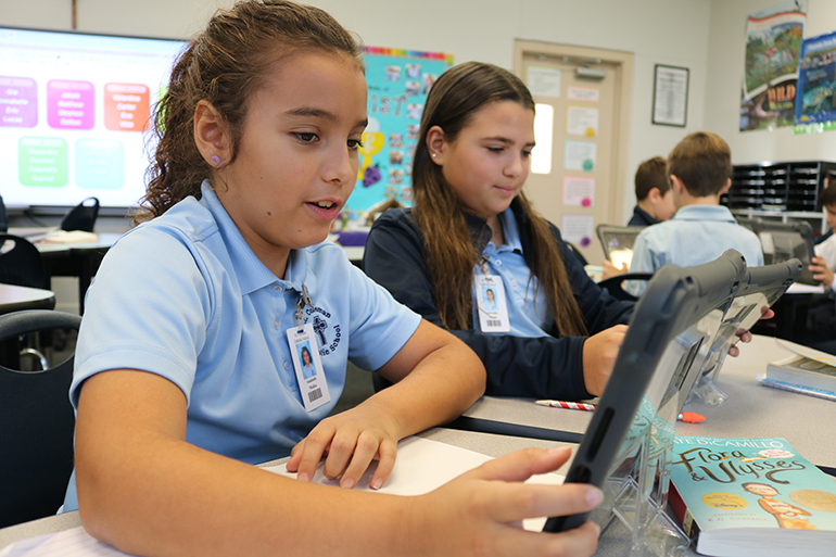 St. Coleman students Annabelle Modica, 9, and Giovanna Martin, 10, work together on a project in reading class using their Apple technology and a little imagination.