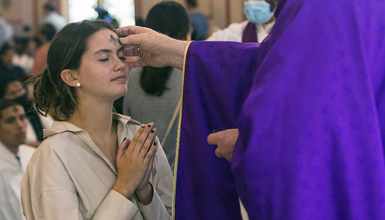 Archbishop Thomas Wenski places ashes on the forehead of Jade Tate, Barry University student, during Ash Wednesday Mass at Gesu Church in downtown Miami, March 2, 2022. He will be celebrating the Ash Wednesday Mass this year, Feb. 22, 2023, at 12:10 p.m. at St. Anthony Church in Fort Lauderdale and Auxiliary Bishop Enrique Delgado will be celebrating the 12:10 p.m. Mass at Gesu.