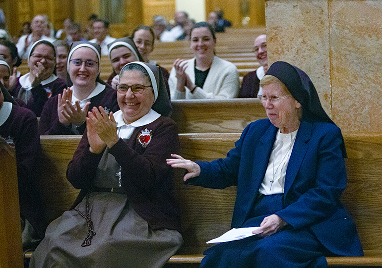 Sister Elizabeth Anne Worley, right, reacts as Archbishop Thomas Wenski recognizes her 60th anniversary in religious life during the Feb. 4, 2023 celebration of the World Day for Consecrated Life. At left is Sister Ana Margarita Lanzas of the Servants of the Pierced Hearts of Jesus and Mary, who serves as directress of the Office for Religious in the Archdiocese of Miami.