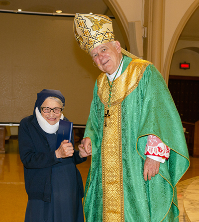 Archbishop Thomas Wenski presents a certificate of appreciation certificate to Sister Clemencia Fernandez, who is marking 75 years with the Daughters of Charity of St. Vincent de Paul, during the celebration of the World Day for Consecrated Life, Feb. 4, 2023 at St. Mary Cathedral.
