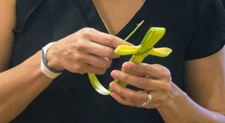 A woman creates a cross from a palm frond during the Palm Sunday Mass celebrated at Miami's St. Mary Cathedral in this file photo. Because they are blessed, these palms are never to be thrown away. The blessed palms can be given back to the church to be burned for Ash Wednesday, or they can be returned to nature by burying or burning them with the ashes spread outside.