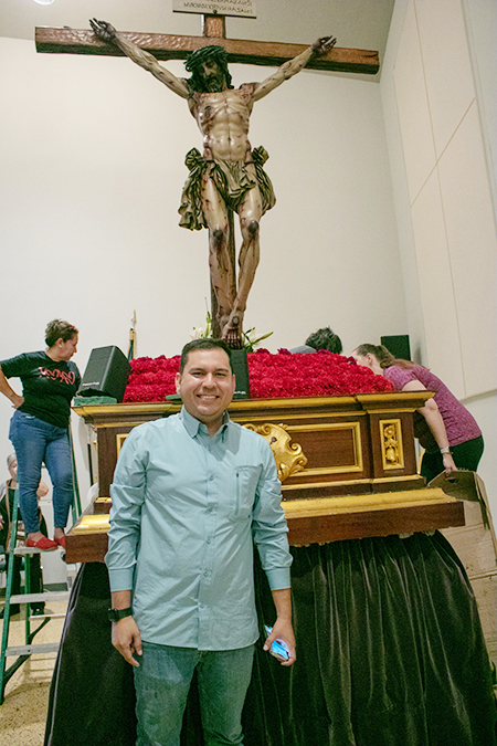 Fabian Sanchez, a member of Corpus Christi Parish's Brotherhood of the Virgin of the Macarena, poses with the image of the Cristo de la Misericordia (Christ of Mercy) as it was decorated to be taken out in procession on Good Friday 2022. Sanchez was the liaison between the parish and the image's sculptor, Juan Manuel Miñarro.