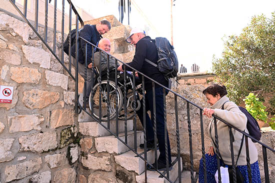 A group of pilgrims assist a man in a wheelchair up to see the the lookout space adjacent to the church on Mount Tabor in Israel, where the New Testament account of the Transfiguration took place. Tourism to Israel and the Holy Land has rebounded following the global pandemic and lockdowns that began in 2020, but the ongoing war between Russia and Ukraine has presented other setbacks.