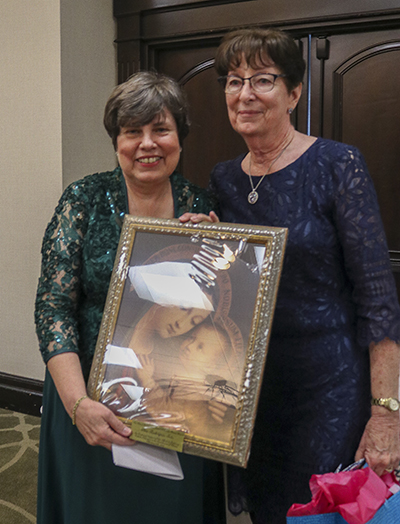 Mary Weber, presidenta del Comité de Becas de MACCW, se retrata con Ana Rodríguez-Soto, editora del Florida Catholic y La Voz Católica, luego de obsequiarle una imagen de la Virgen María. Rodríguez-Soto fue la homenajeada de este año por sus esfuerzos para fomentar la educación católica en la Arquidiócesis de Miami, el 25 de febrero de 2023, en Fort Lauderdale.