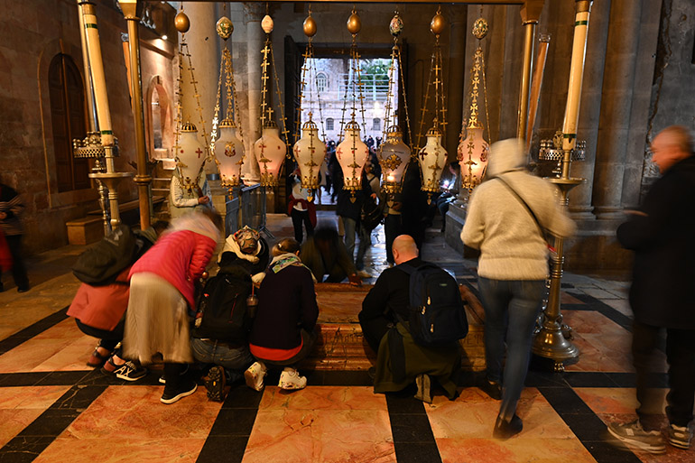 Pilgrims pass by the "Stone of Unction" at the Church of the Holy Sepulchre in Jerusalem, where tradition holds that Christ's body was laid and prepared for burial.