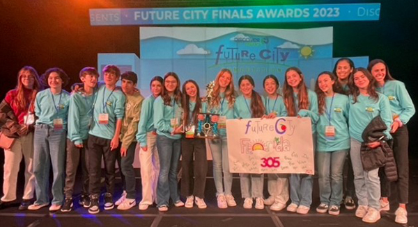 Eighth graders from St. Hugh School in Miami pose on stage at the Future City international contest in Washington, D.C in February 2023, where the group placed fourth for their model city, Imperium-Aqua. Earlier in the year, they won first place in the Tampa Bay, Florida regional contest.