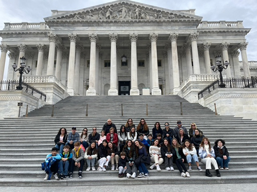 Eighth graders from St. Hugh School in Miami, along with family and friends, sit on the steps of the Capitol Building in Washington, D.C. during a break from their Future City international contest in February 2023, where they placed fourth for their model city Imperium-Aqua. Earlier in the year, they won first place in the Tampa Bay, Florida regional contest.