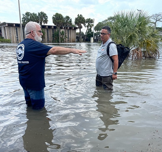 Father Joseph Maalouf, left, wades through the floods surrounding St. Jerome Church on April 13, 2023. With him is Fernando Peña of the Servpro clean-up and recovery company. (Courtesy)