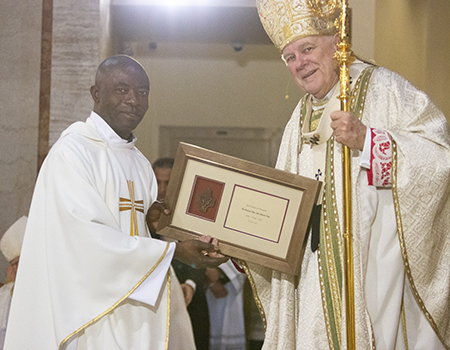 Father Yaw John Aduseh-Poku, currently serving as parochial vicar at St. Edward Church, Pembroke Pines, is congratulated by Archbishop Thomas Wenski on his 25th anniversary in the priesthood, a recognition that took place during the chrism Mass at St. Mary Cathedral, April 4, 2023.