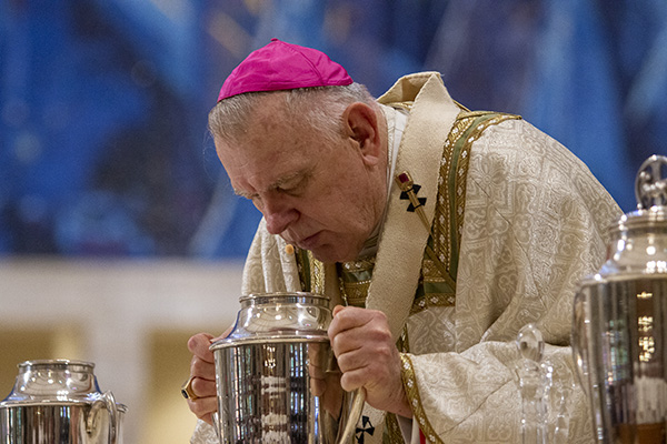 Archbishop Thomas Wenski consecrates the oil of chrism by breathing over it during the chrism Mass celebrated at St. Mary Cathedral, April 4, 2023.