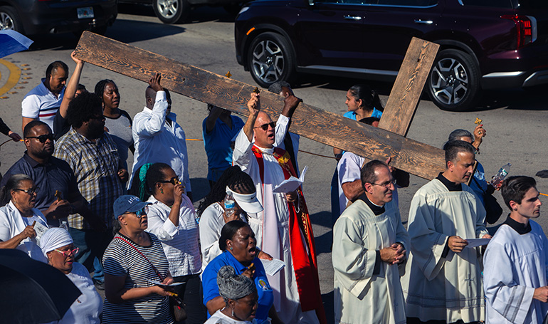 Father Christopher Marino, St. Mary Cathedral's rector, center, walks alongside parishioners during a Good Friday procession around the cathedral, April 7, 2023.