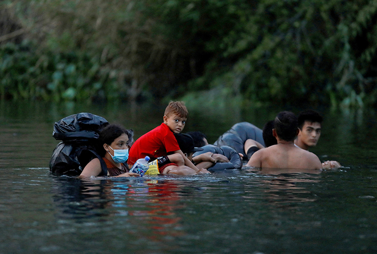 Migrantes ingresan al río Bravo en Matamoros, México, el 10 de mayo de 2023, para cruzar la frontera y entregarse a los agentes de la Patrulla Fronteriza de Estados Unidos antes de que finalice el Título 42.