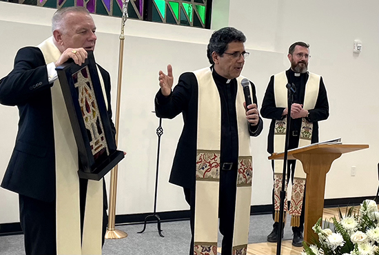 Father Juan Carlos Paguaga explains the symbolism of the stained glass brick given to benefactor Mary M. Spencer as parochial vicar Father Andrzej Foltyn looks on, during the dedication of the new sports and multipurpose center at St. Agnes Parish in Key Biscayne, May 15, 2023.