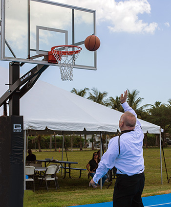 Archbishop Thomas Wenski makes the inaugural basket at the dedication of St. Lawrence School's state-of-the-art basketball-volleyball court, May 16, 2023.